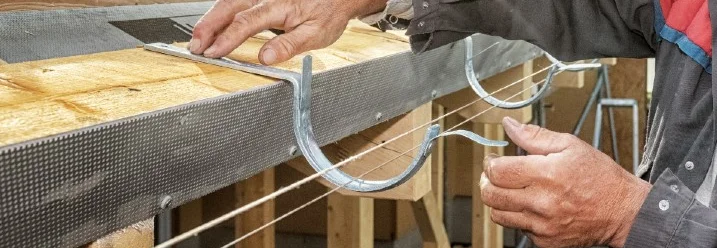 Person montiert Dachrinne an Dach